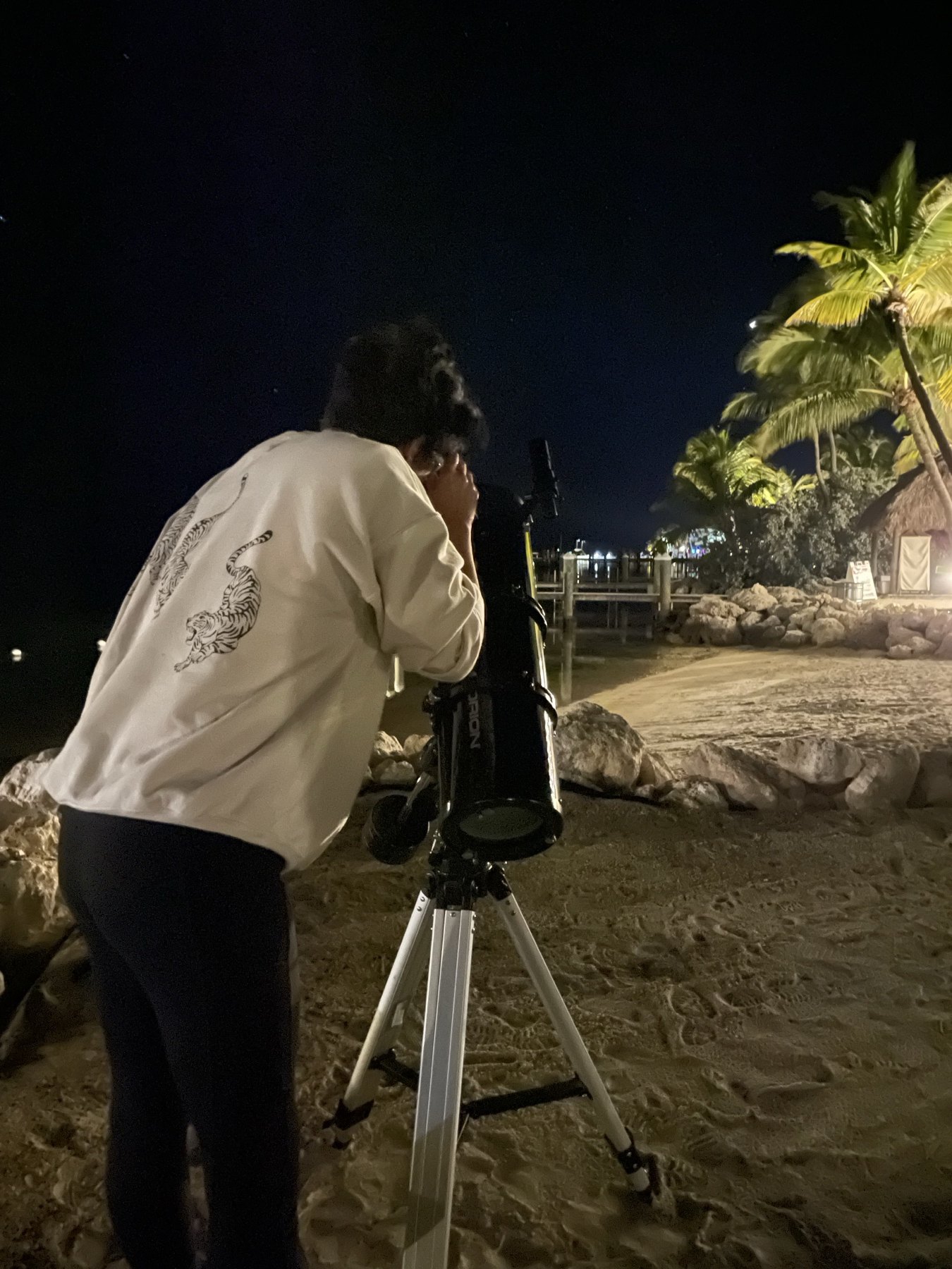 Guest looking through a telescope during a beach astronomy program
